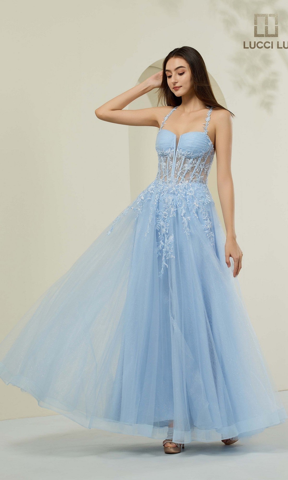 A woman poses against a neutral background in the Lucci Lu 1444 long prom dress, featuring an A-line silhouette, powder blue tulle fabric, and lace detailing.